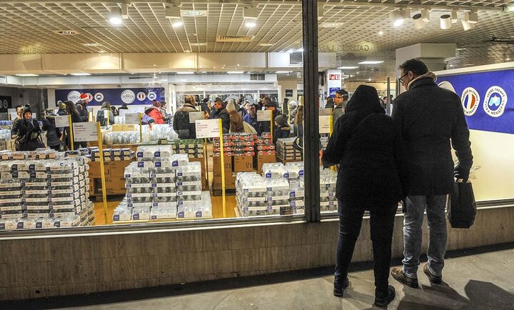 L'intérieur de la boutique Duralex d'Orléans. On voit de nombreux clients faire leurs achats, avec des étagères remplies de produits Duralex en verre, tels que des verres, plats et autres articles. L'ambiance semble animée avec de nombreuses personnes présentes dans le magasin.